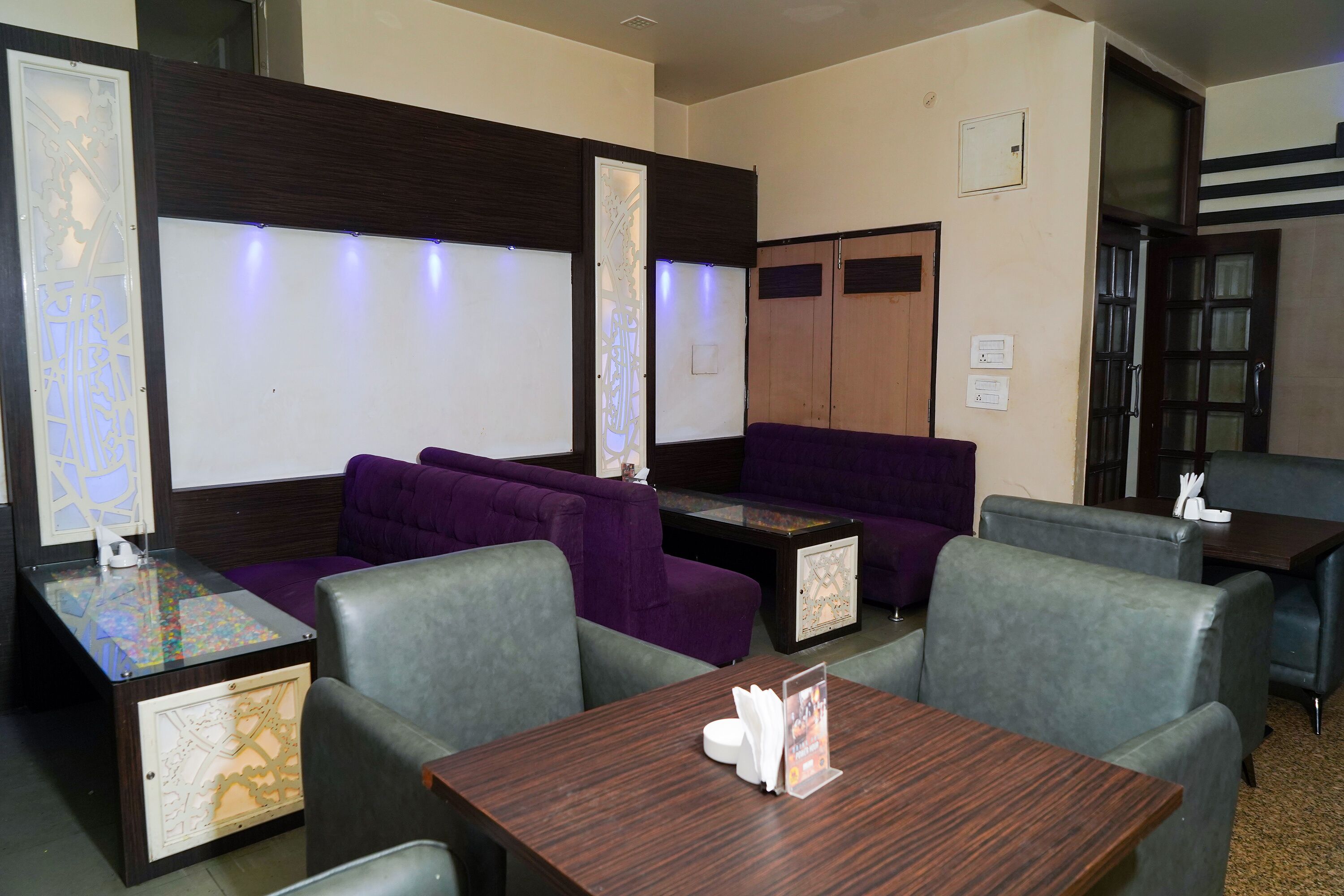A hotel lobby with seating areas, a reception desk, and a wooden partition with frosted glass panels.