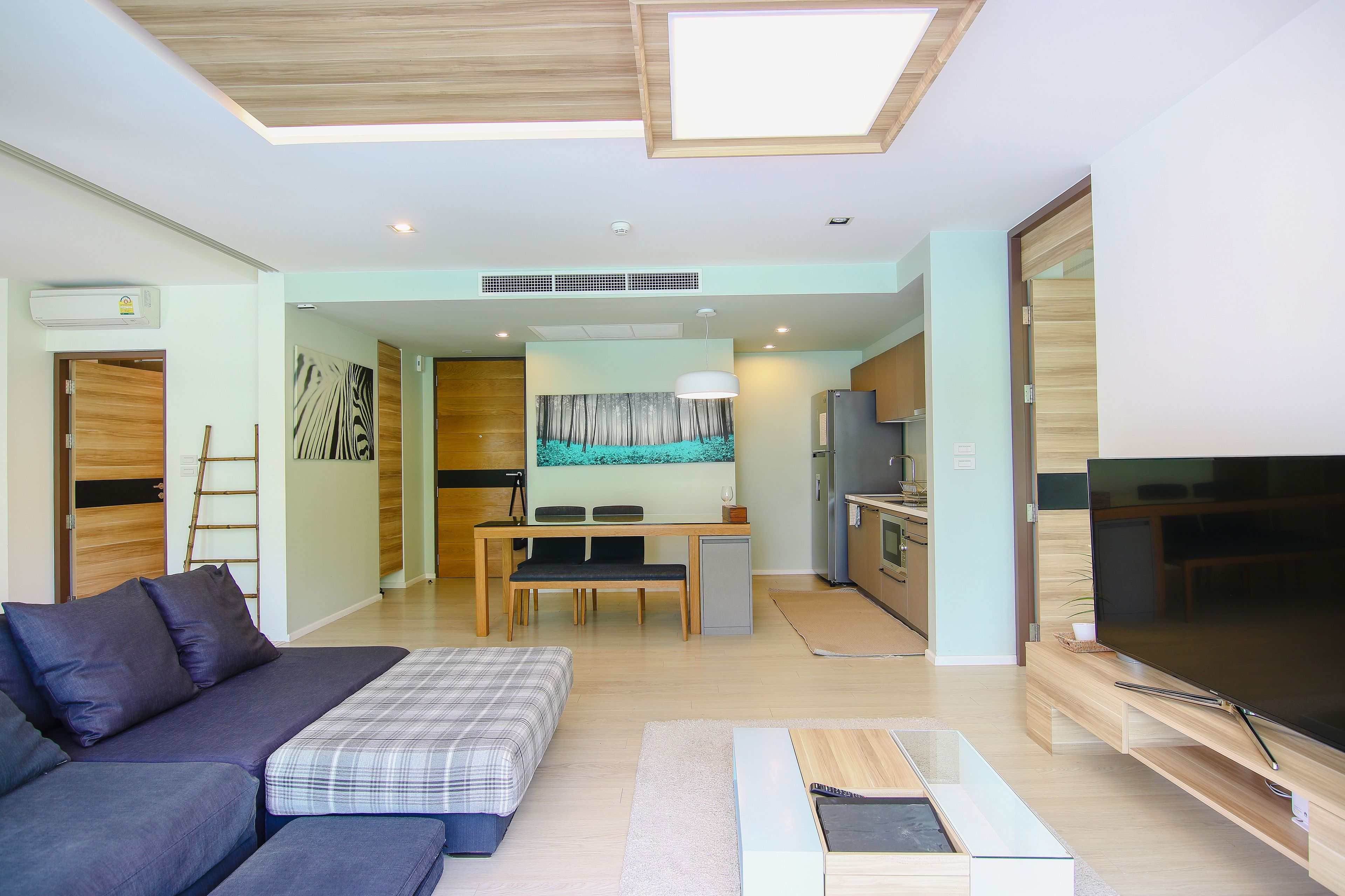 A modern living room with a sofa, a TV, and a dining area with a table and chairs.