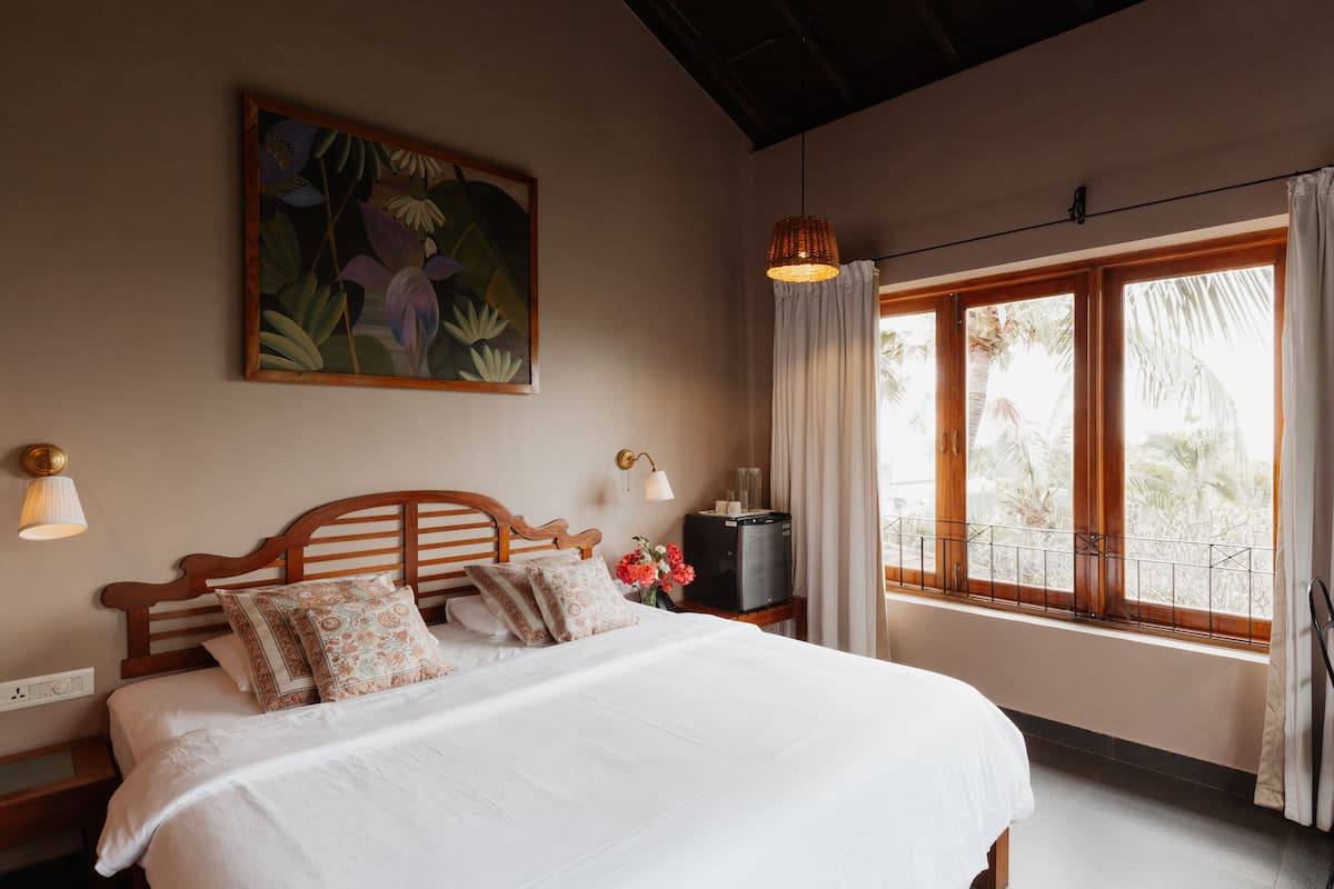 Quarto com uma cama grande, mesa de cabeceira, televisão e janela com cortinas.