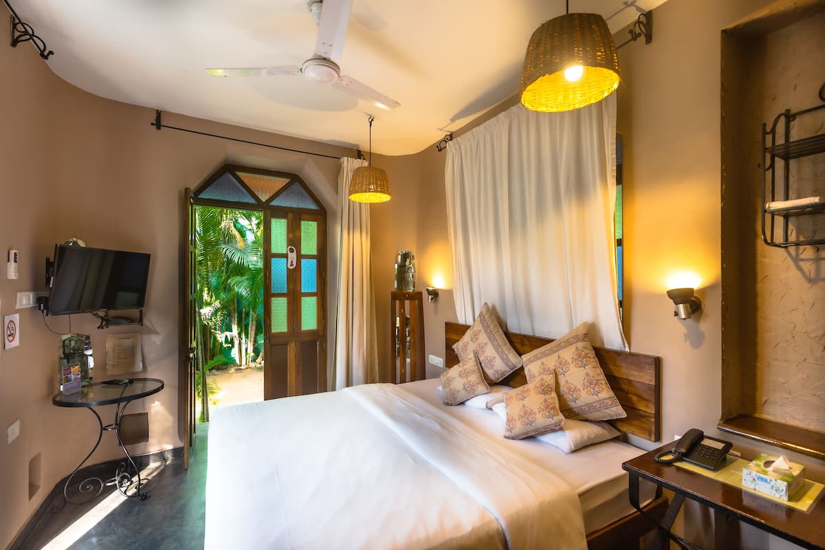 Quarto de hotel com cama, escrivaninha, televisão e vista para o exterior.