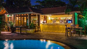 A bar area with a pool, outdoor seating, and tropical plants. - Fiesta Beach Resort (Baga)