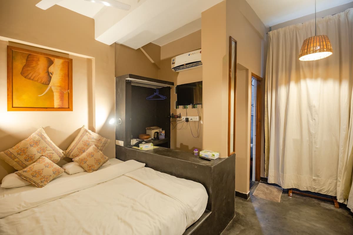 Quarto com cama, luminária pendente, espelho e ar-condicionado fixado na parede.