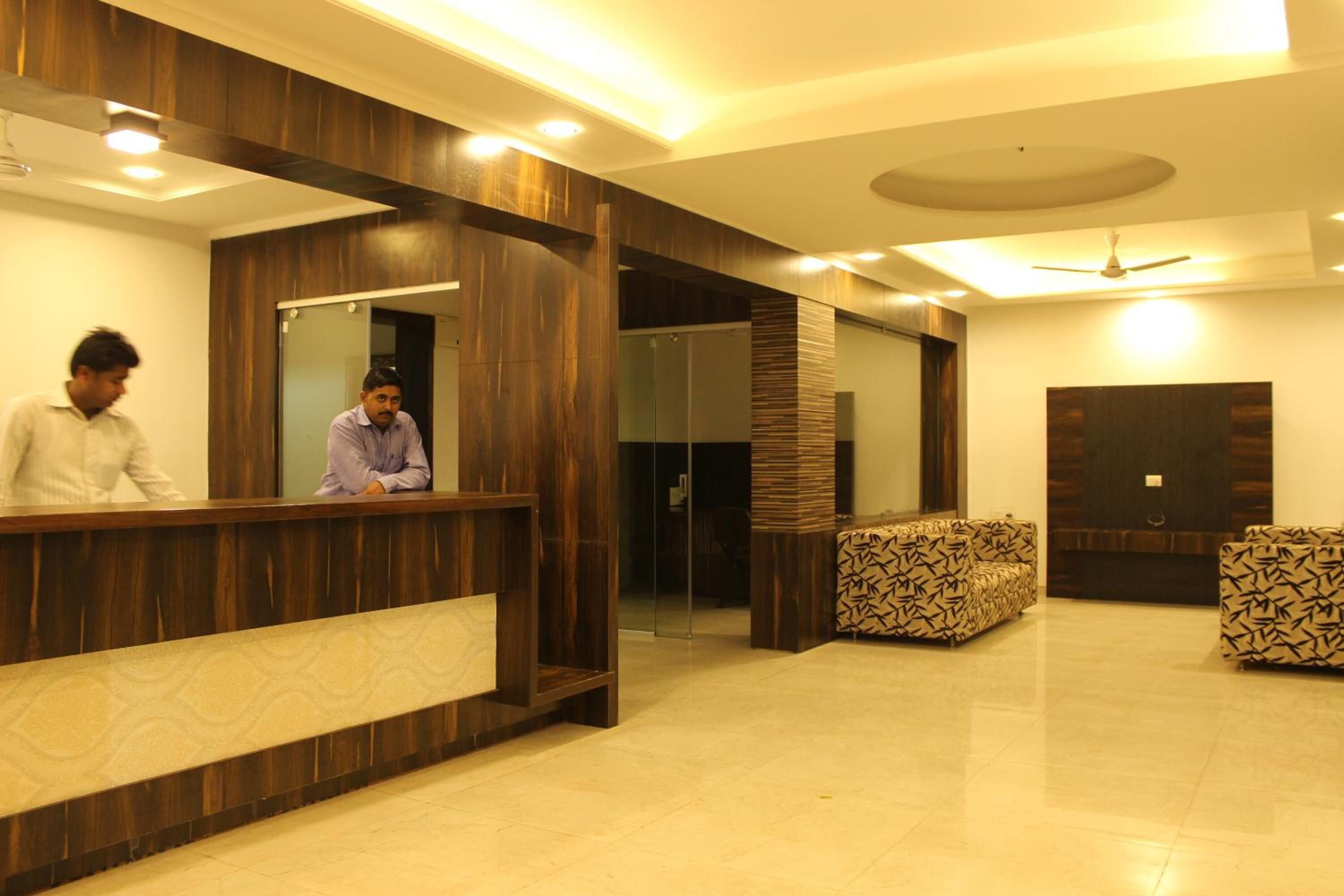 A reception area with a wooden reception desk, two patterned sofas, and a ceiling fan.