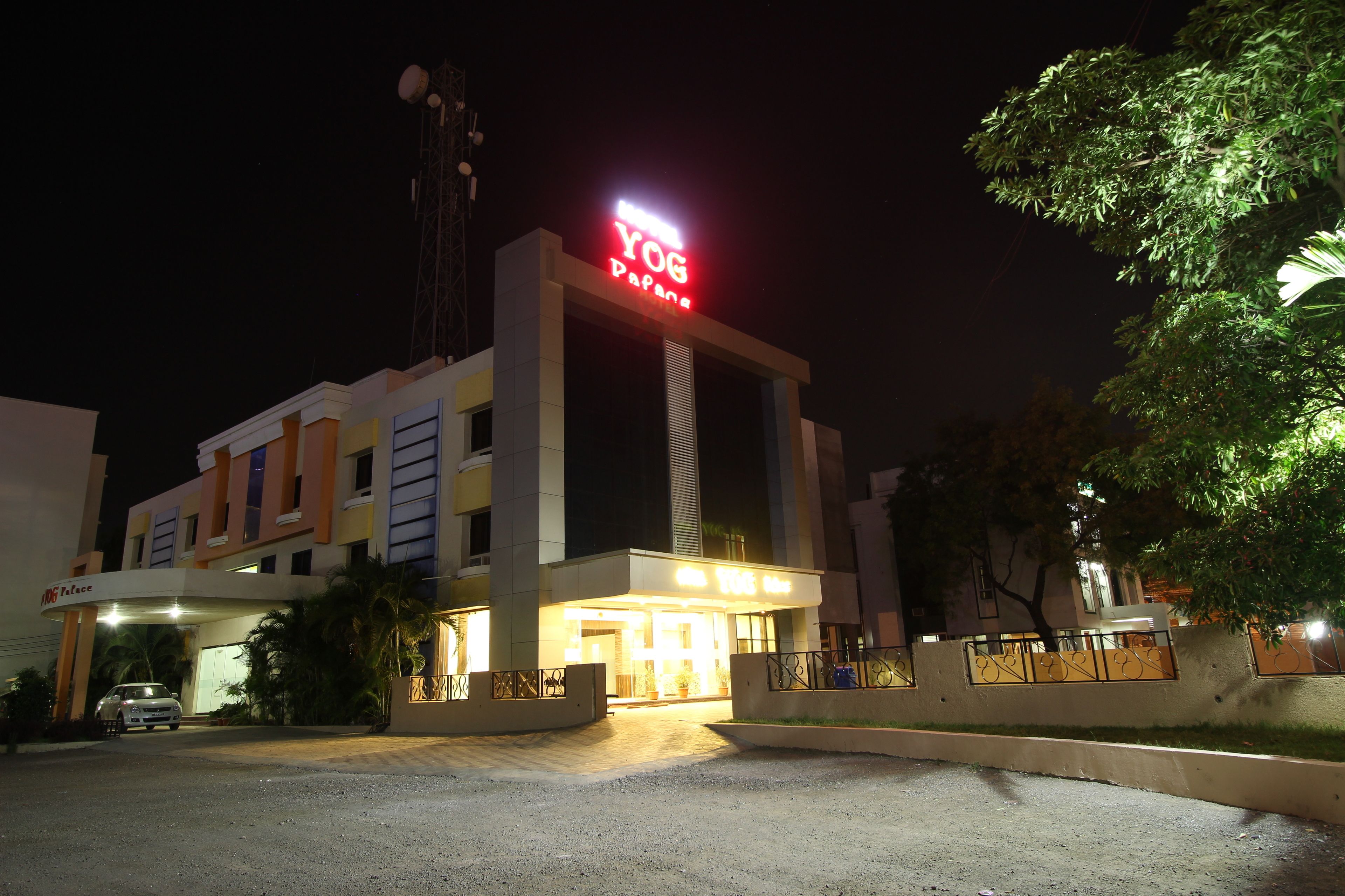 A hotel with a prominent 'YOG' sign, a well-lit entrance, and a gated driveway.