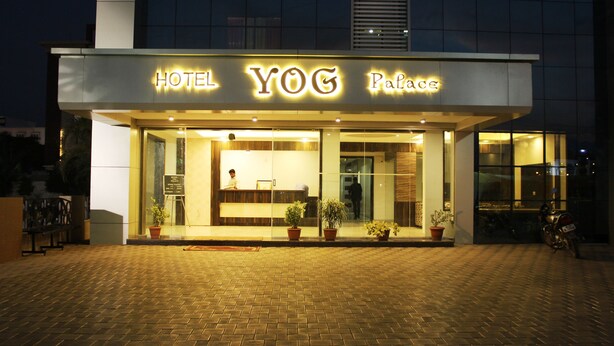 A hotel named "Hotel YOG Palace" with a reception area, potted plants, and a motorcycle parked outside. - Hotel Yog Palace (Rahata)