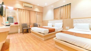 A hotel room with two beds, a desk, a chair, and an air conditioning unit. - Hotel Yog Palace (Rahata)