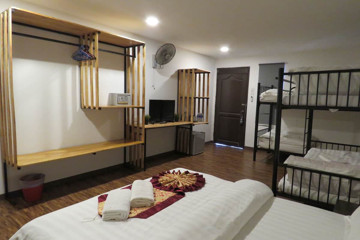 Una habitación de hotel con literas, un escritorio, un televisor y un ventilador.