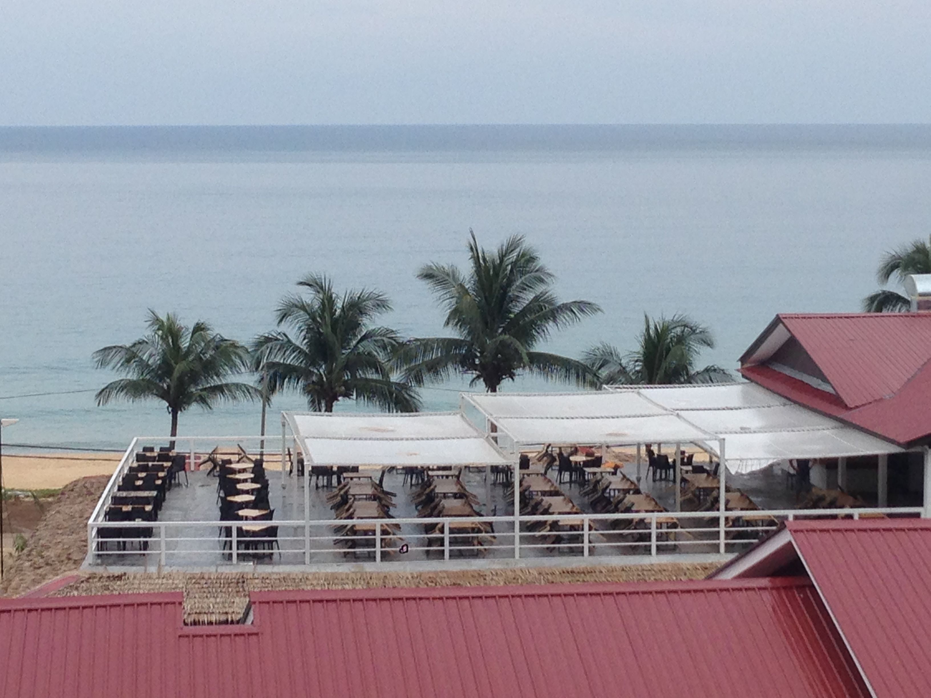 A beachside restaurant with outdoor seating and palm trees.