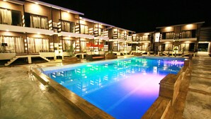 Un hotel con piscina, varios balcones y zonas de estar al aire libre.
