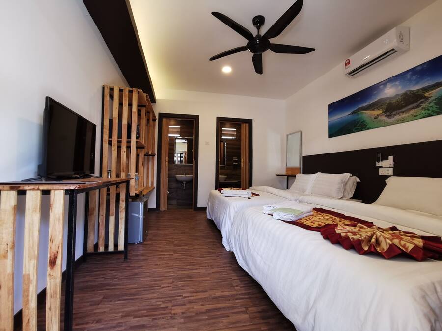 A hotel room with a bed, a TV, a ceiling fan, an air conditioner, and a painting on the wall.