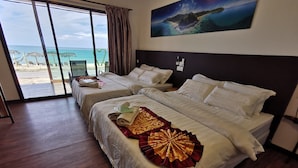Habitación de hotel con dos camas, un ventanal con vista a la playa y un cuadro en la pared.