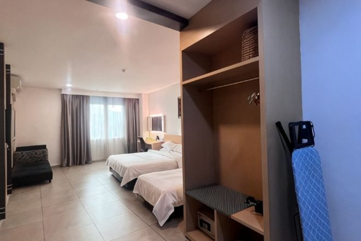 A hotel room with two beds, a wardrobe, a desk, and a chair.