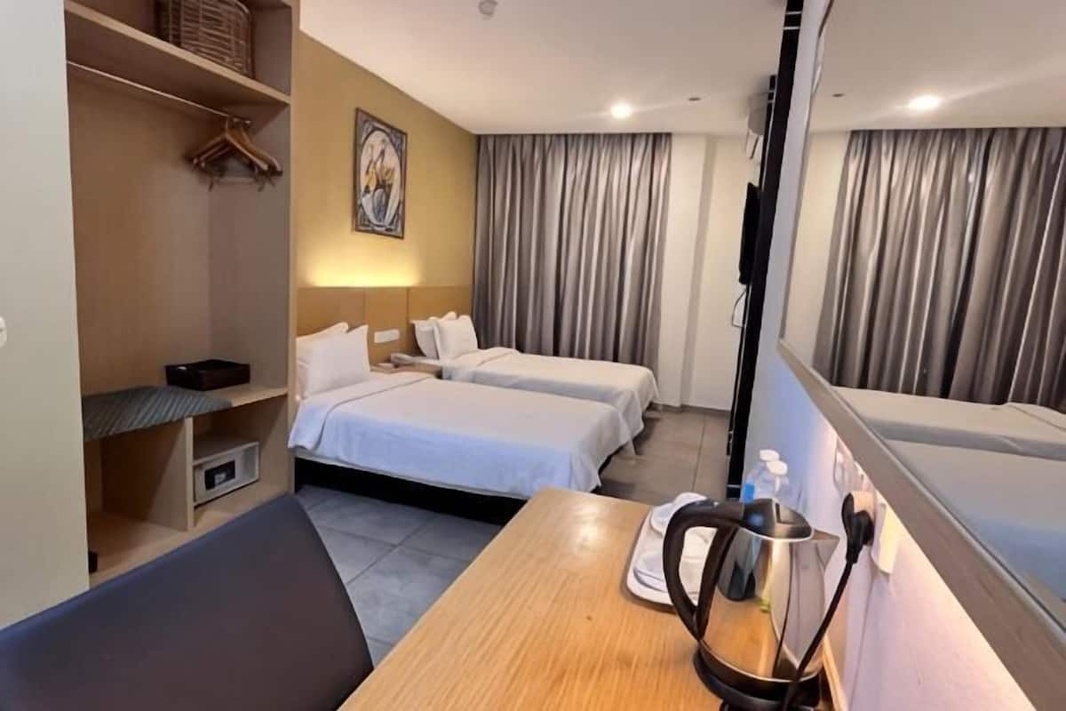 A hotel room with two beds, a wooden table, a TV, and a bathroom with a bathtub.