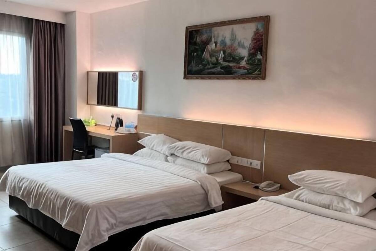 A hotel room with two beds, a desk with a chair, a painting on the wall, and a nightstand with a phone.