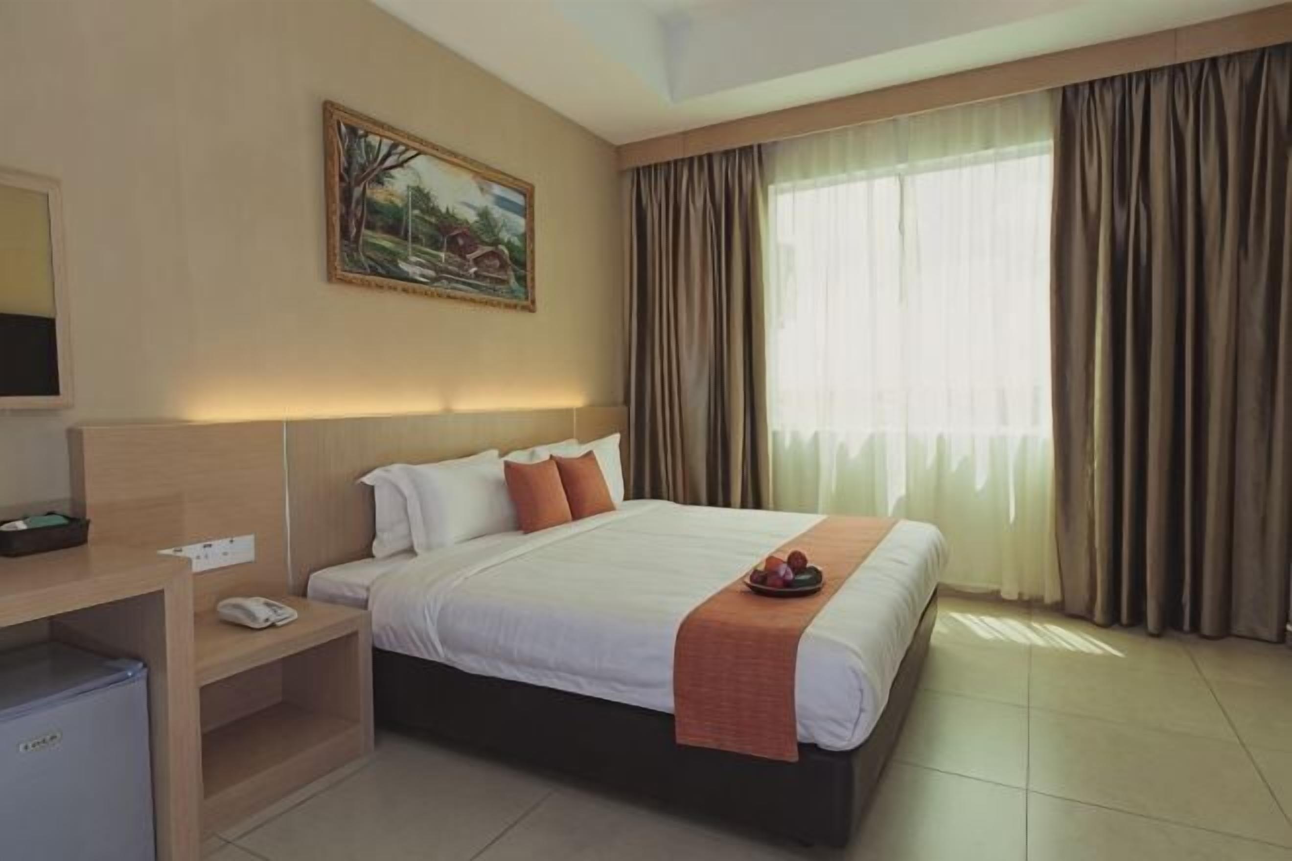 Una habitación de hotel con una cama, un escritorio, un televisor y un cuadro en la pared.