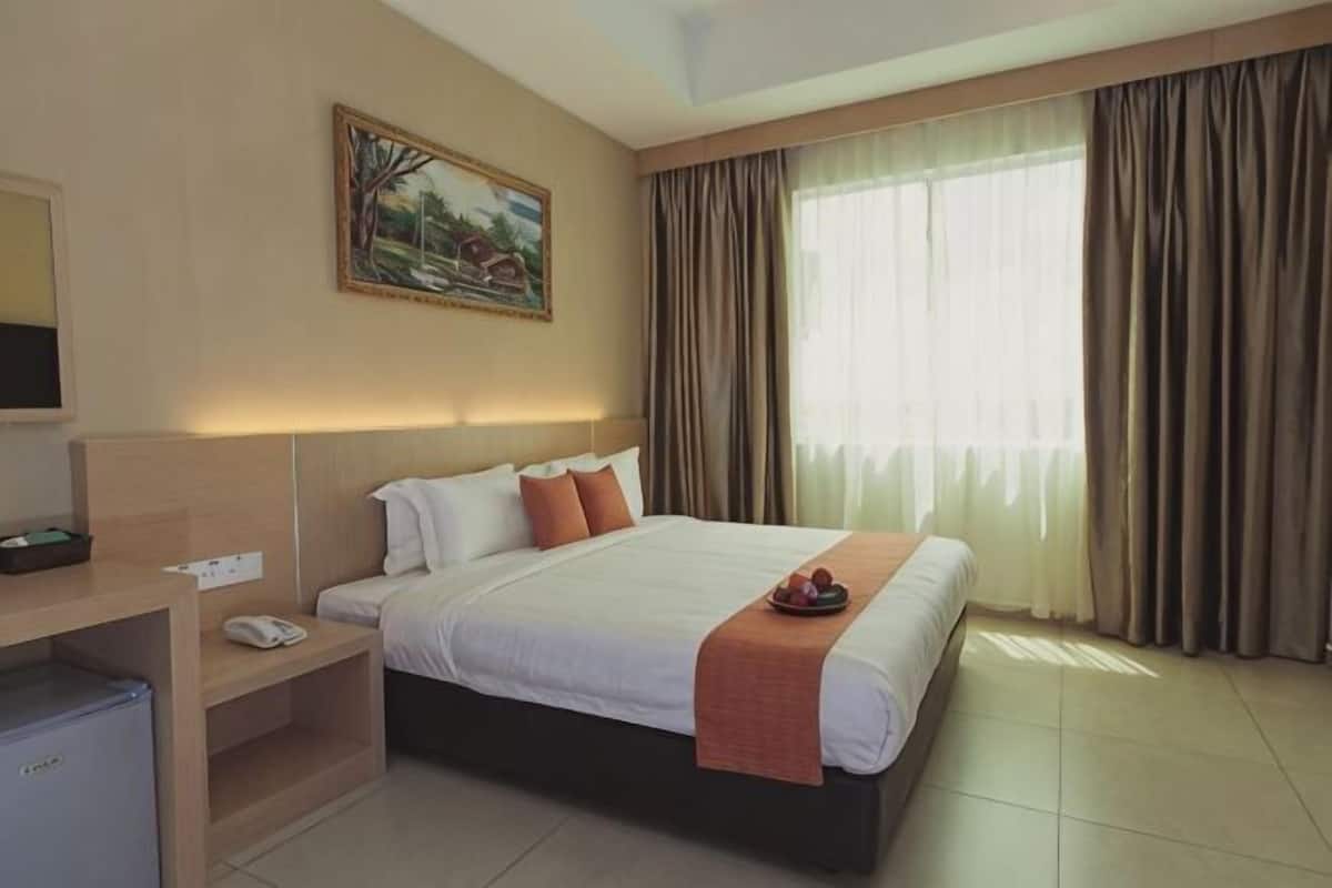 A hotel room with a bed, a desk, a television, and a painting on the wall.