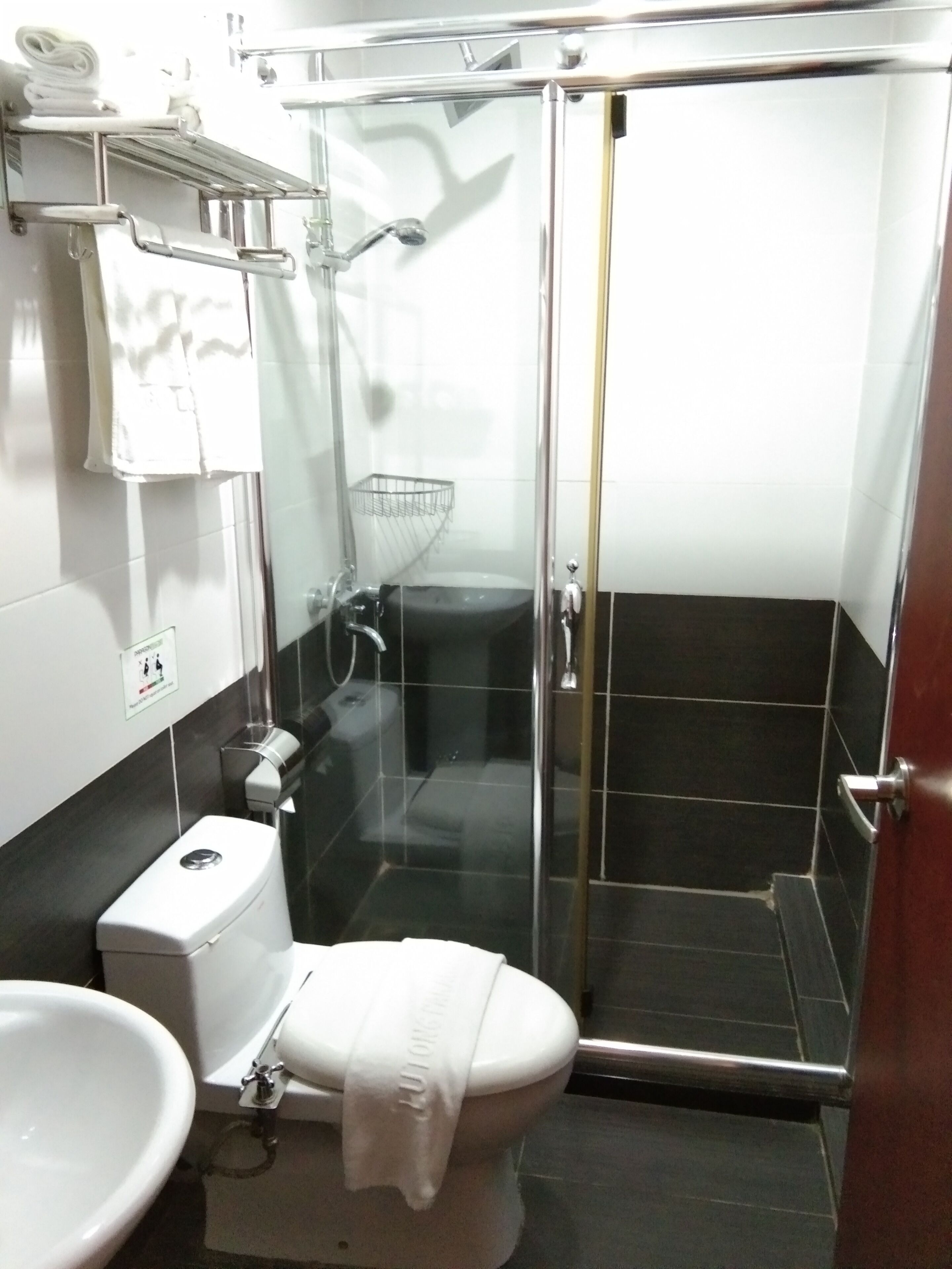 Un baño pequeño y moderno con ducha envuelta en vidrio, inodoro blanco y lavamanos.