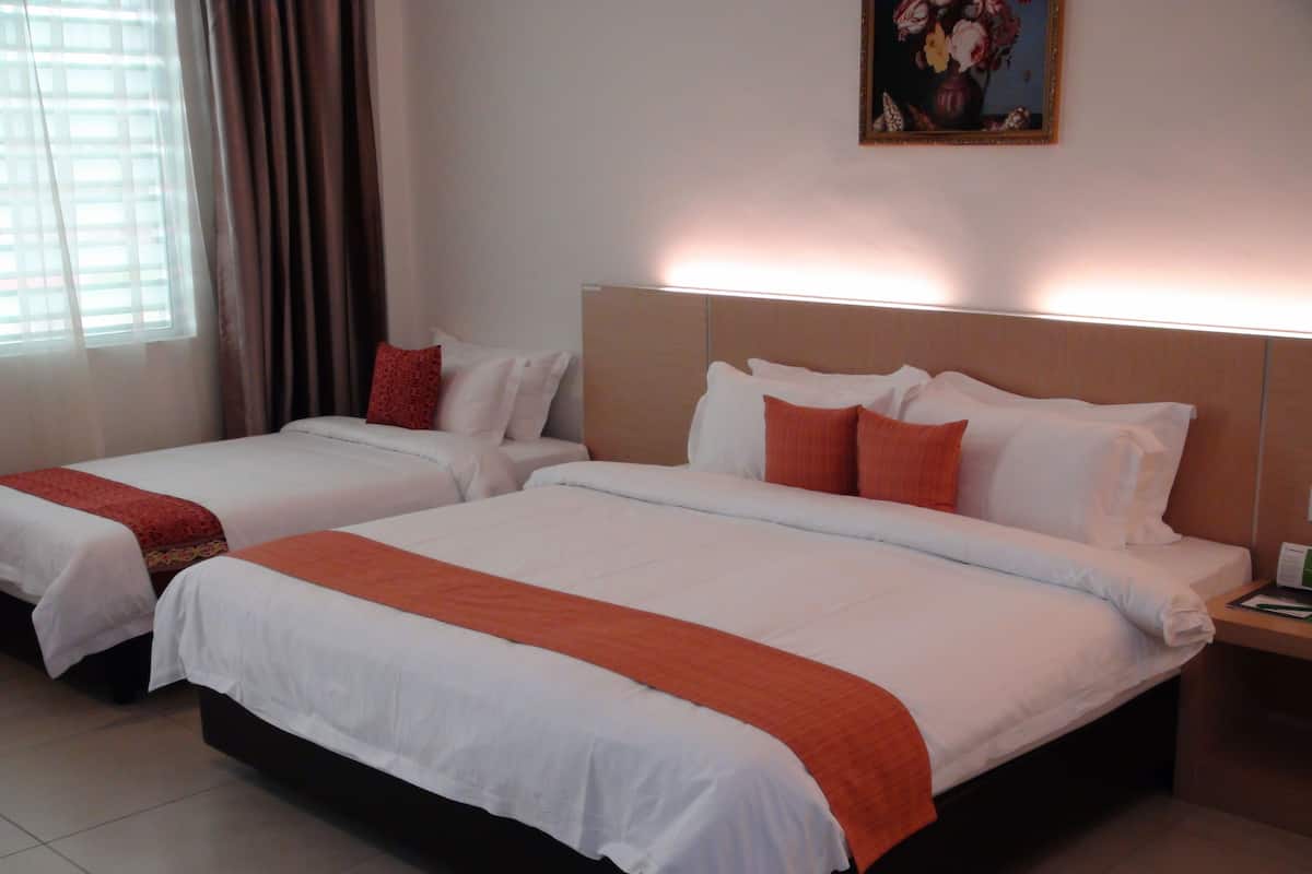 A hotel room with two beds, each with white linens and orange accents, a painting on the wall, and a window with curtains.