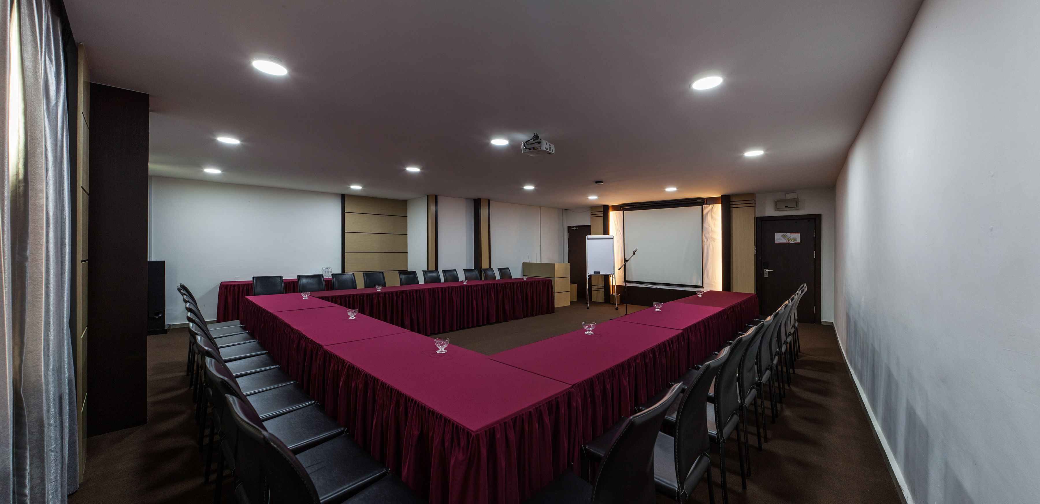 Uma sala de conferência com uma mesa comprida, cadeiras, um projetor e um quadro branco.