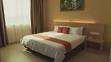 Habitación de hotel con una cama grande, una mesita de noche con un teléfono y un cuadro en la pared.