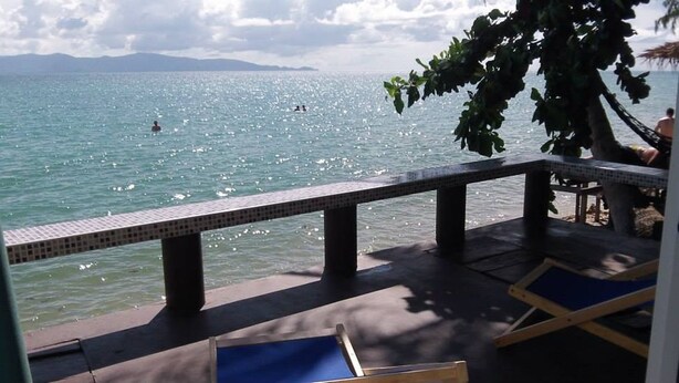 A poolside area with a tiled deck, lounge chairs, and a view of the sea. - Zen Zi Beach Rooms (Ko Pha-ngan)