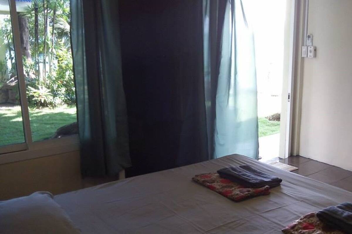 Een hotelkamer met een bed, een klein tafeltje en uitzicht op een tuin door een raam.