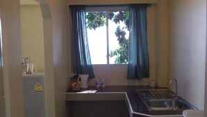 A small kitchenette with a window, a sink, and a refrigerator. - Zen Zi Beach Rooms (Ko Pha-ngan)