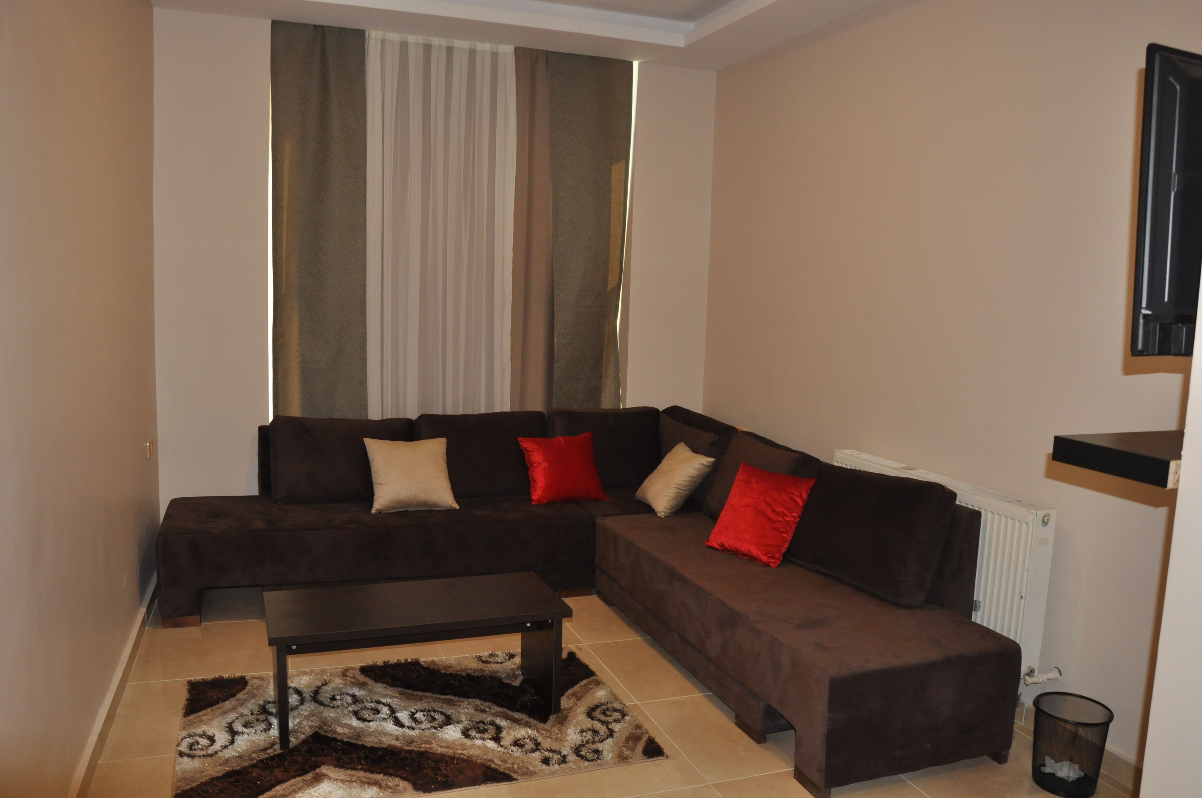 A living room with a brown sectional sofa, a coffee table, and a patterned rug.