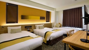 Ein Hotelzimmer mit drei Betten, einem Holztisch und einem großen Spiegel an der Wand.