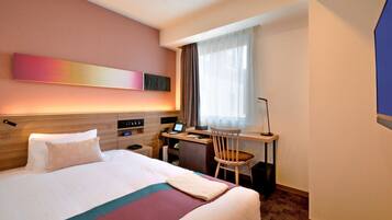 A hotel room with a bed, desk, chair, and a large window with curtains.