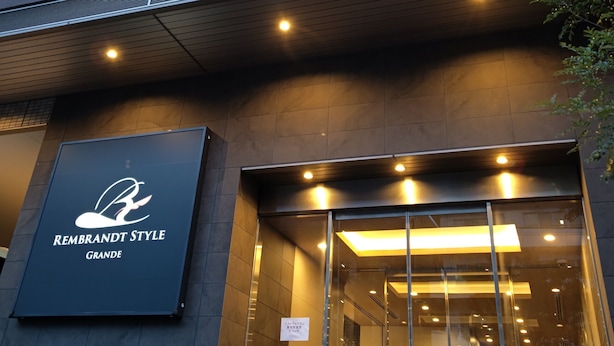 A modern building with a sign reading "REMBRANDT STYLE GRANDE" and a glass entrance.