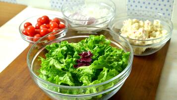 A salad bowl with lettuce and cherry tomatoes on a wooden table.