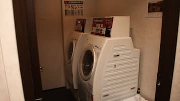 A laundry room with two stacked washers and dryers, a small shelf with a bottle, and a door labeled "Private".