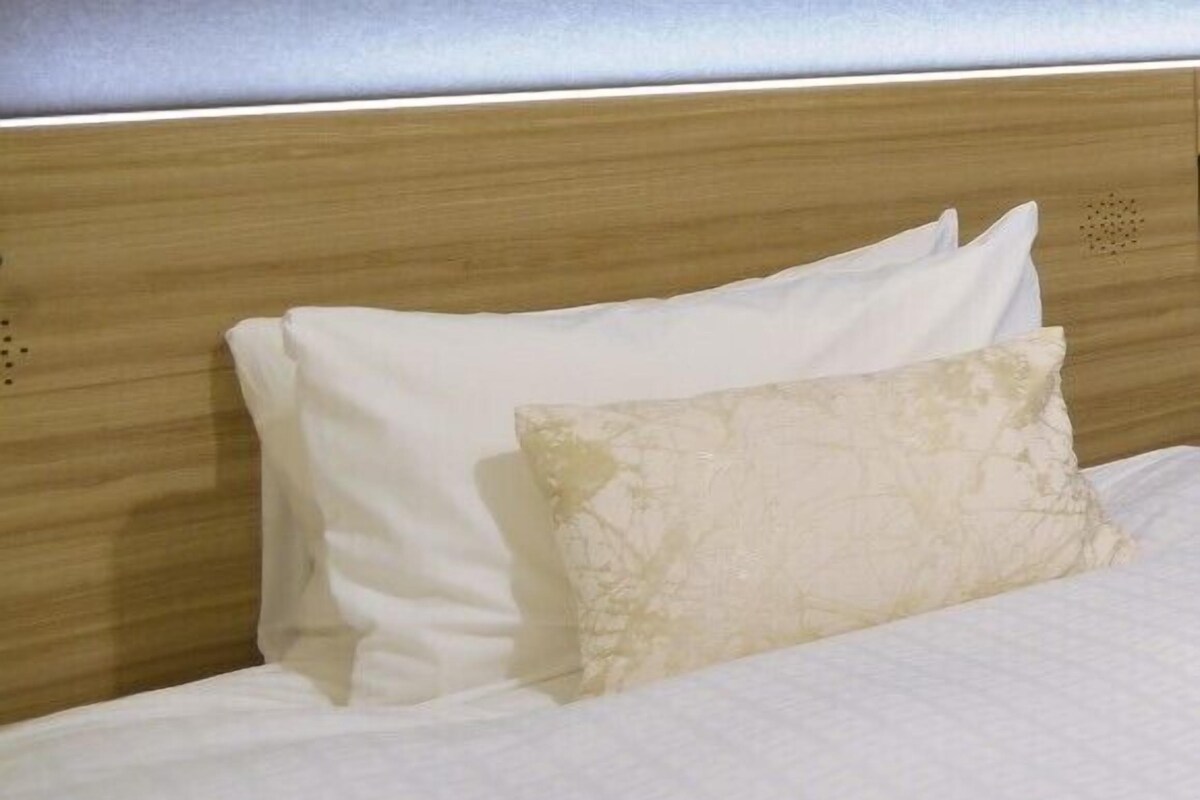 A bed with white bedding and a wooden headboard.