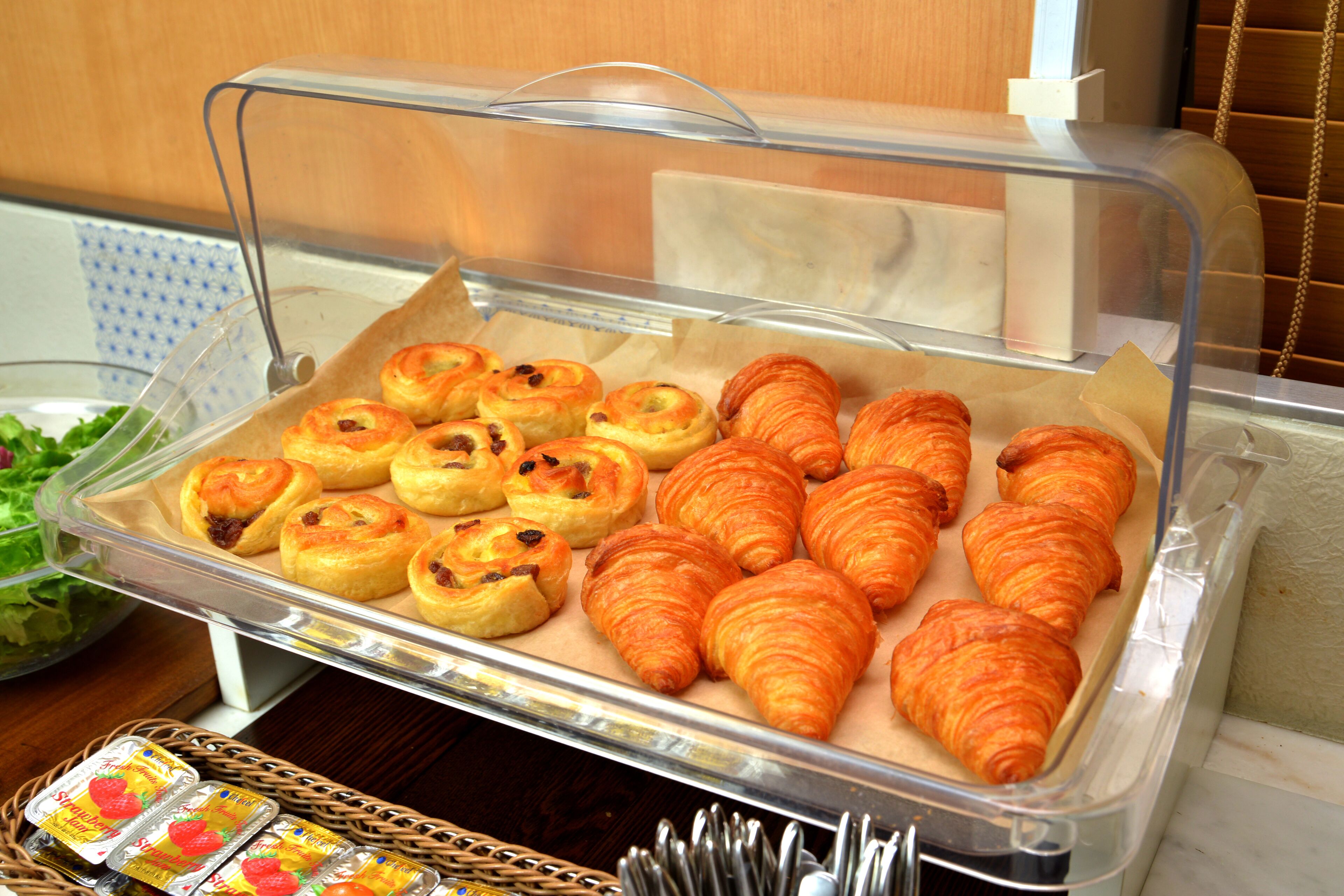 A buffet with pastries and a salad.