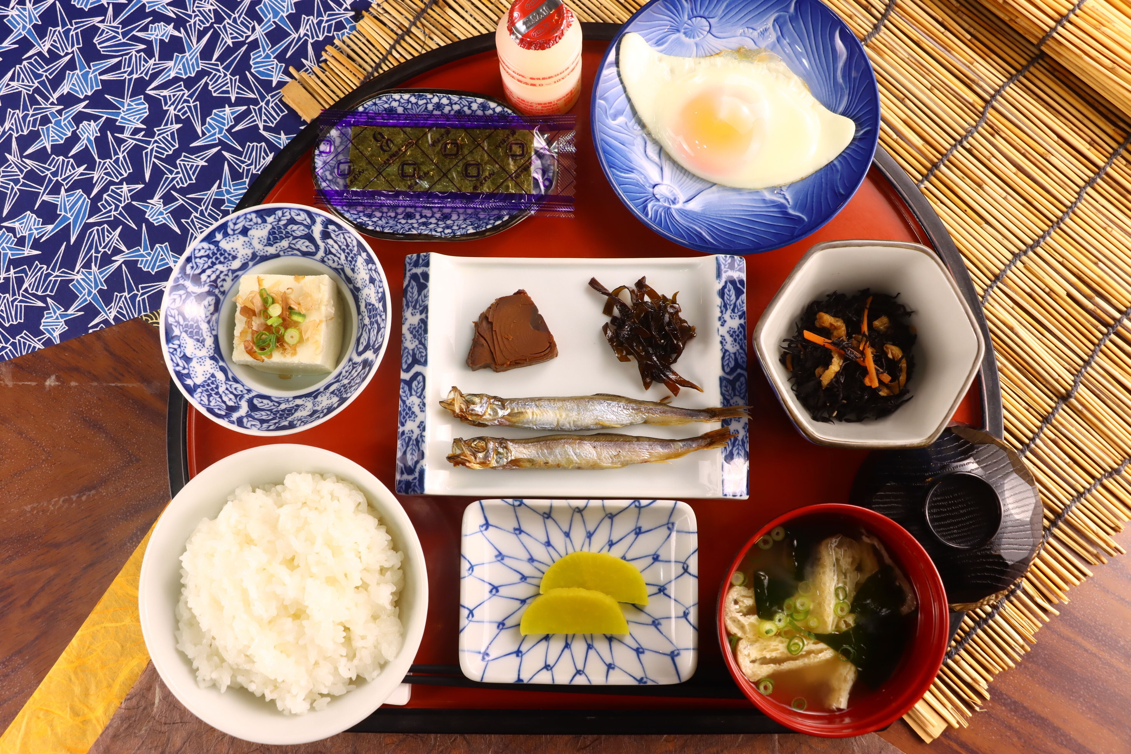 Un plateau contenant divers plats japonais, notamment du riz, du poisson et un bol de soupe.