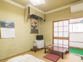 Una habitación japonesa tradicional con suelo de tatami, una puerta corredera shoji, un televisor y un calendario en la pared.