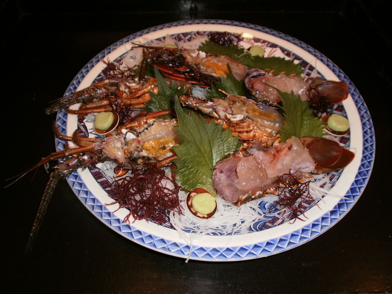 Prato de frutos do mar com camarão e caranguejo, decorado com folhas e fatias de pepino.