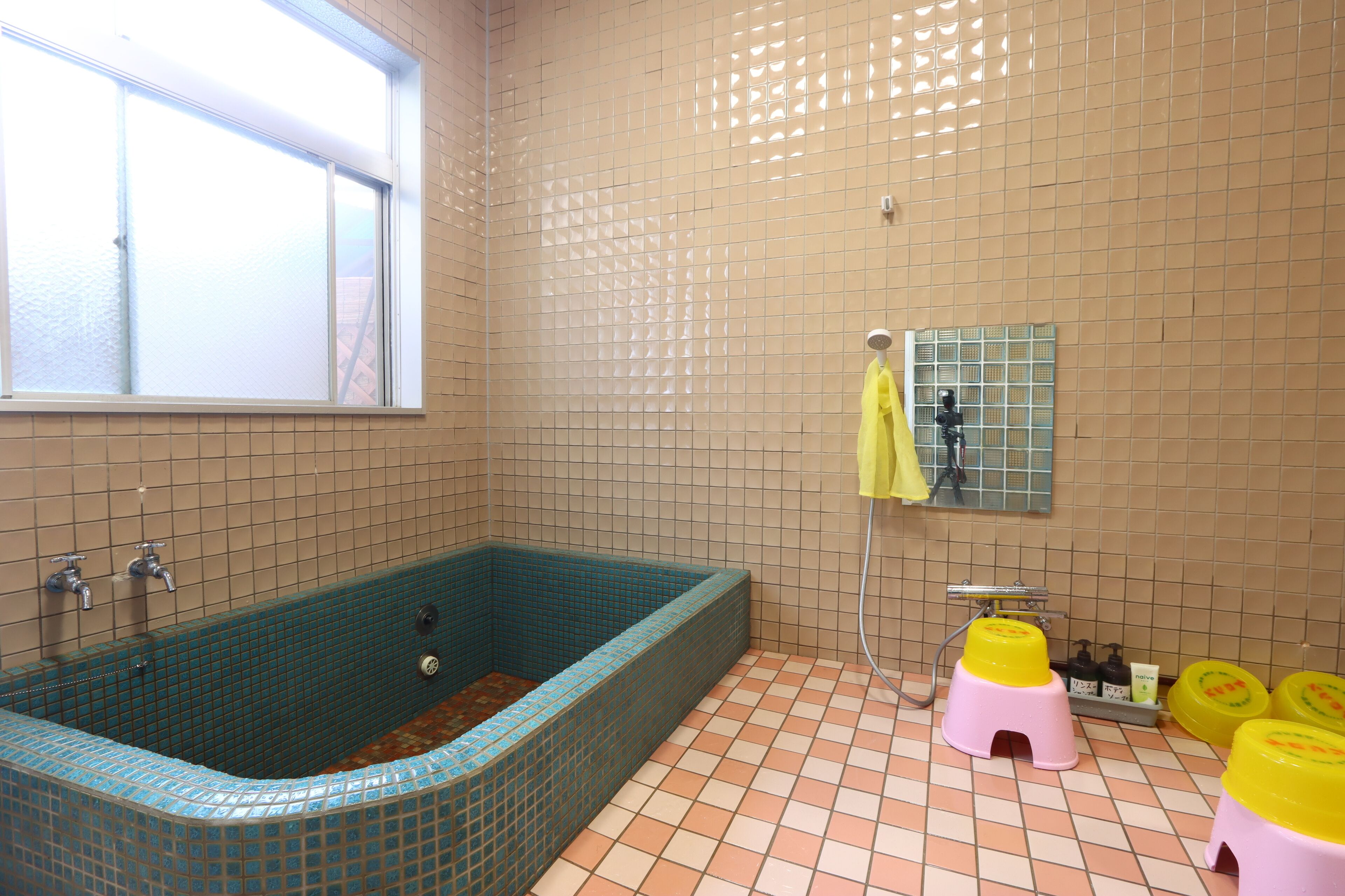 Une salle de bain avec une baignoire, une fenêtre et des murs carrelés.