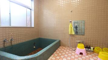 Une salle de bain avec une baignoire, une fenêtre et des murs carrelés.