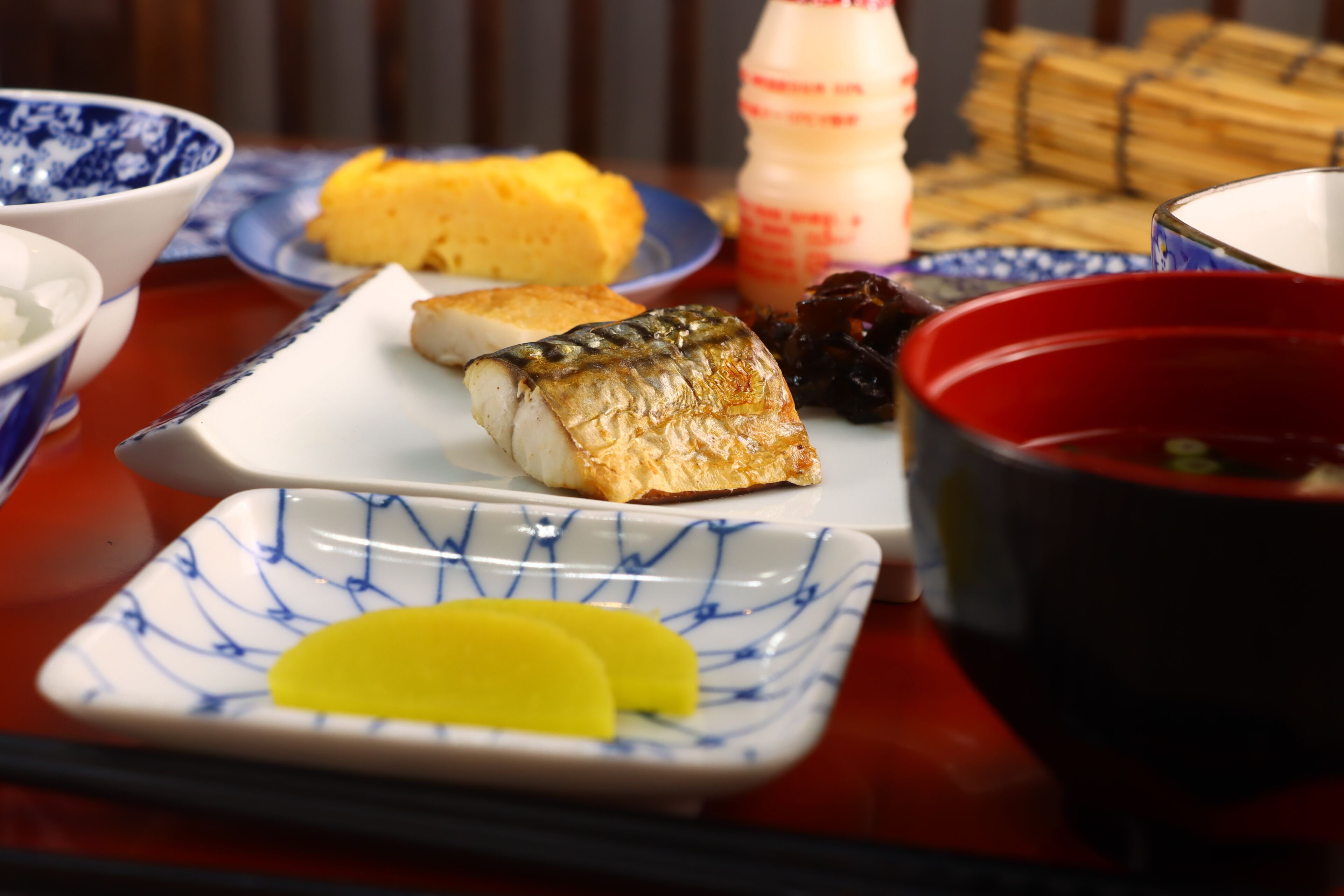 Een tafel met verschillende gerechten, waaronder sushi, ingelegde groenten en een fles saus.