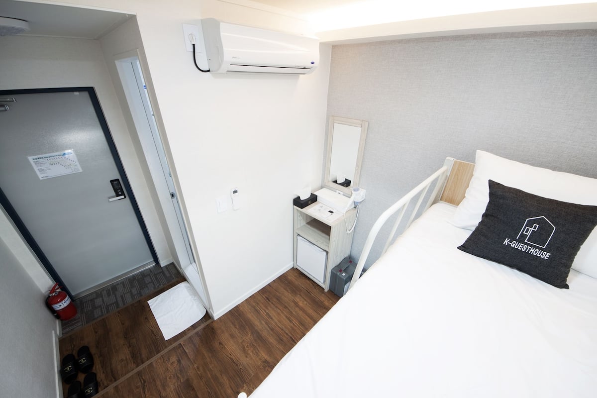 Een hotelkamer met een bed, een bureau, een spiegel en een deur.