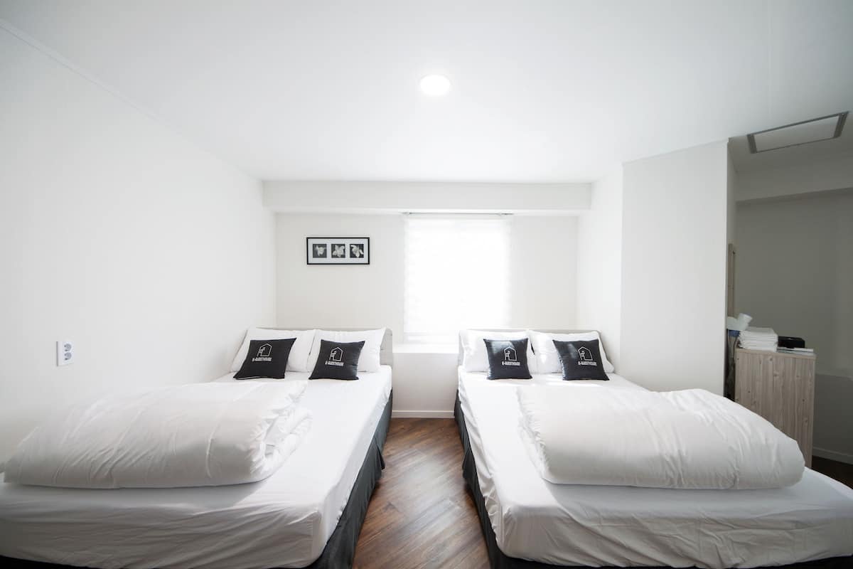 Een tweepersoonskamer met twee bedden, een raam en een klein bureau.