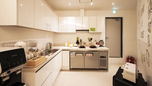 A modern kitchen with white cabinets, a coffee machine, a refrigerator, and a microwave. - Seoul Grand Hostel Ewha Univ. (Seoul)