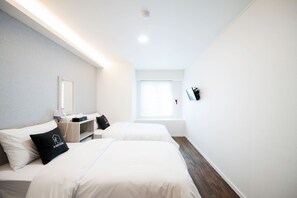 Moderni hotellihuone, jossa on kaksi sänkyä, yöpöytä, peili ja ikkuna.