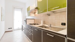Une cuisine moderne dotée d’une cuisinière à gaz, d’un évier en acier inoxydable et de meubles de rangement aux couleurs sombres.