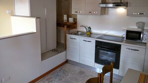 Una cocina compacta con armarios blancos, una campana extractora de acero inoxidable, un microondas y un lavavajillas.