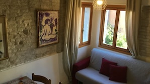 Una habitación acogedora con una pared de piedra, un cuadro enmarcado, un sofá con cojines rojos y una lámpara colgante.