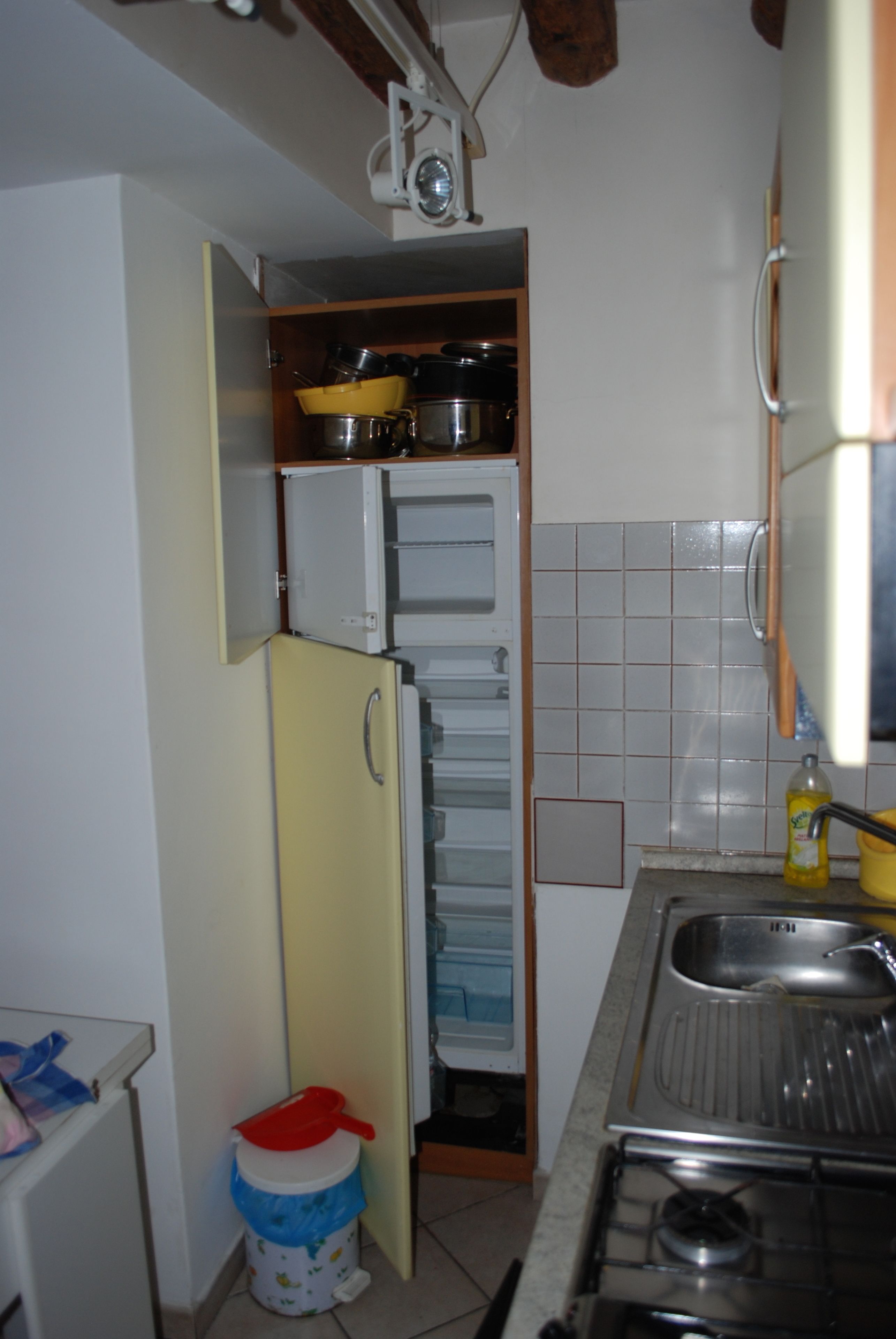 Een kleine keuken met een koelkast, een spoelbak en een fornuis.
