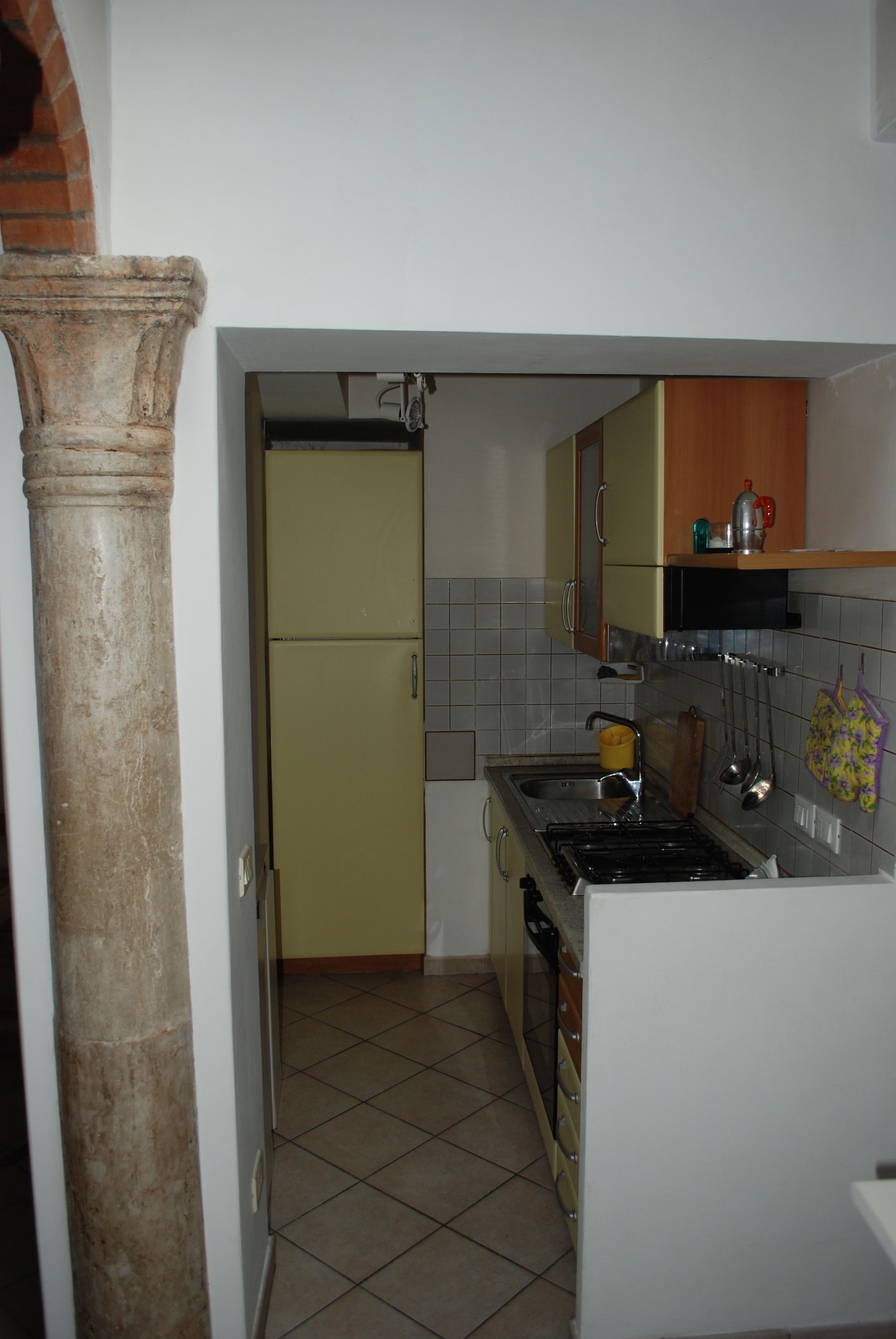 A kitchen with a tiled floor, a stove, a sink, and cabinets.